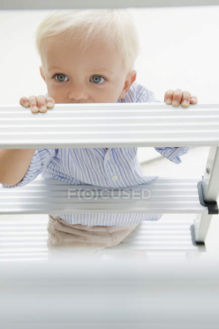 Lindo niño rubio de pie en la escalera de paso - foto de stock