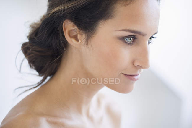 Retrato de mujer sonriente con maquillaje elegante mirando hacia otro lado - foto de stock