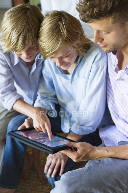 Homme et deux petits garçons regardant tablette numérique — Photo de stock