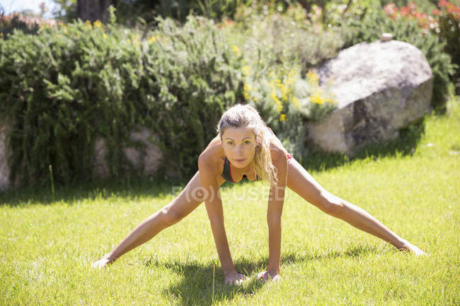 Mujer deportiva haciendo ejercicio en el césped en el jardín - foto de stock