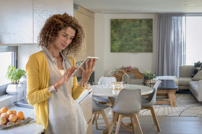 Жінка використовує цифровий стіл на сучасній кухні — стокове фото