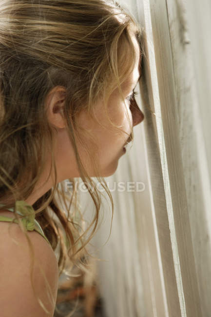 Крупный план маленькой девочки, подглядывающей через забор — стоковое фото