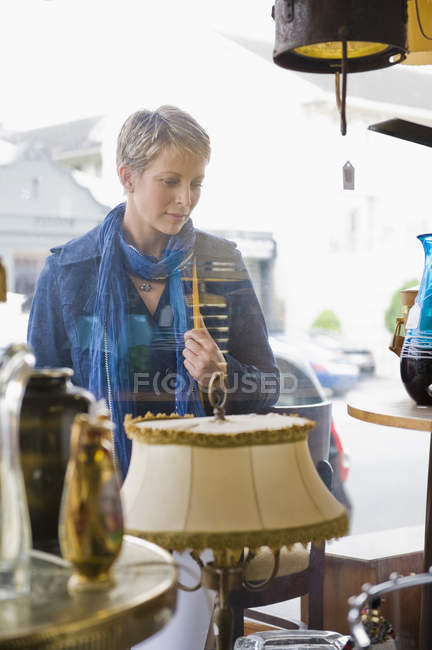 Mature woman looking at window of antique store — Stock Photo