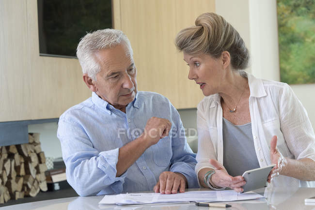 Casal sênior focado classificando contas na mesa em casa — Fotografia de Stock