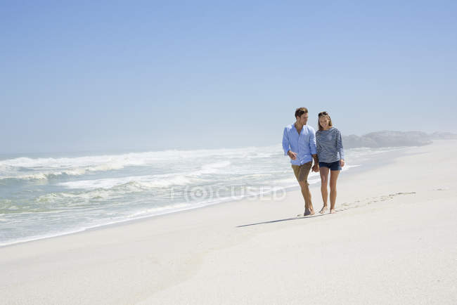 Casal feliz andando na praia de areia de mãos dadas — Fotografia de Stock
