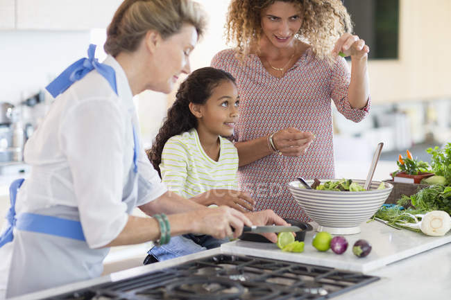 Senior woman with daughter and granddaughter preparing food in kitchen — Stock Photo