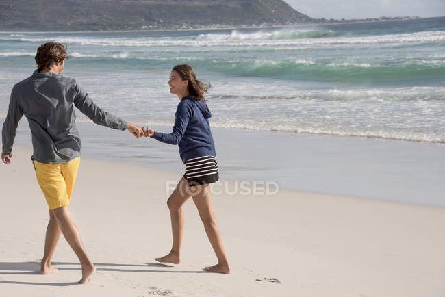 Молода пара ходить на пляжі тримаючись за руки — стокове фото