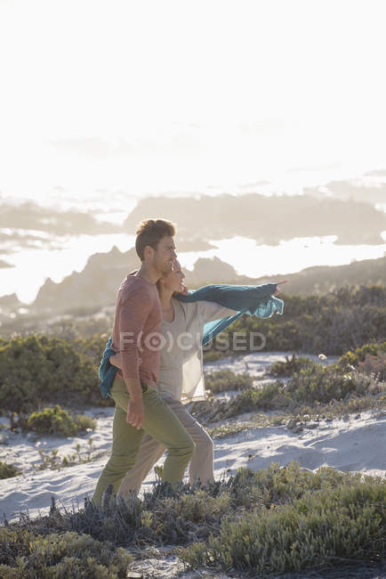 Pareja romántica caminando en la costa juntos en la luz del sol - foto de stock