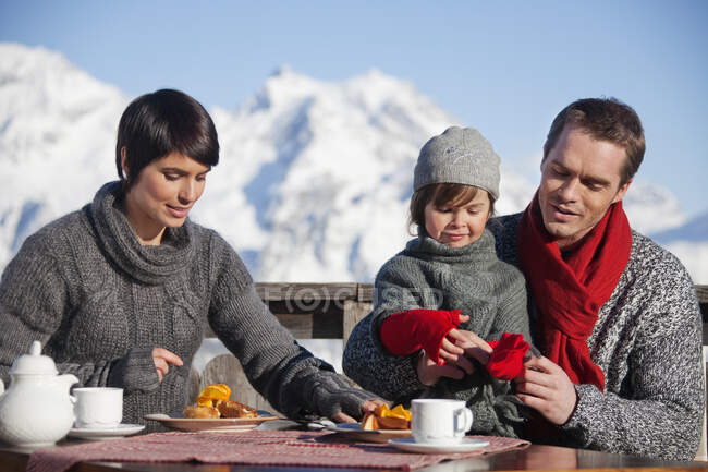 Casal e filha comendo na varanda na estância de esqui — Fotografia de Stock