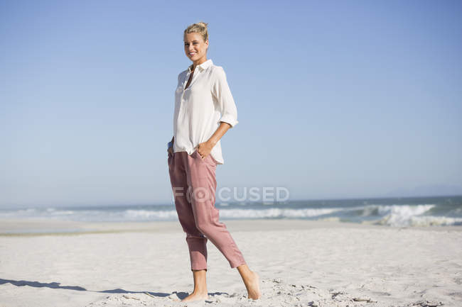 Portrait of slim young woman standing on sunny beach — Stock Photo