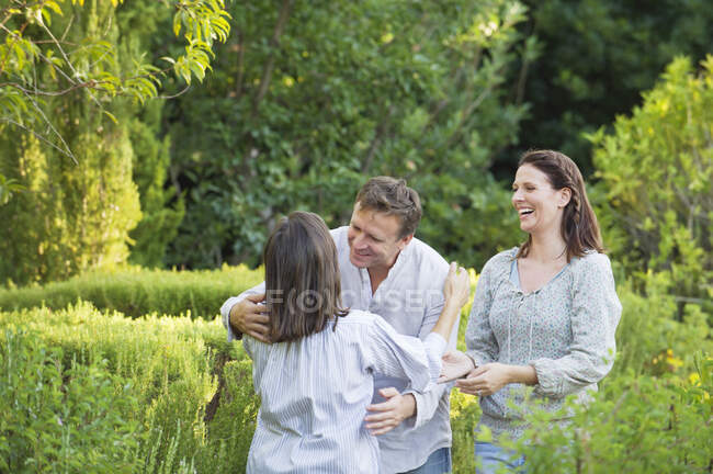 Зрелая пара обнимает свою мать в саду — стоковое фото