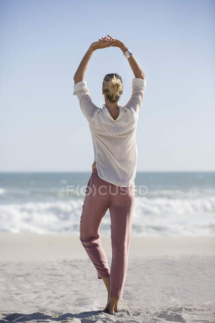 Relaxed young woman doing yoga on sunny beach — Stock Photo