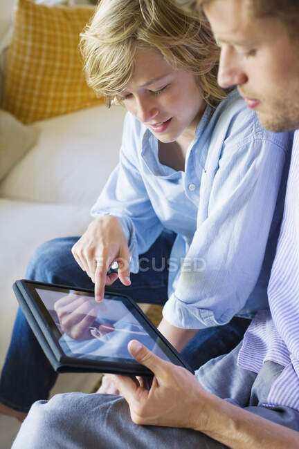 Человек и маленький мальчик смотрят на цифровой планшет — стоковое фото