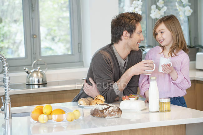 Мужчина пьет чай с дочерью на кухне — стоковое фото