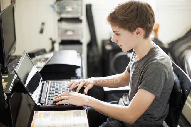 Adolescente menino digitando no laptop — Fotografia de Stock
