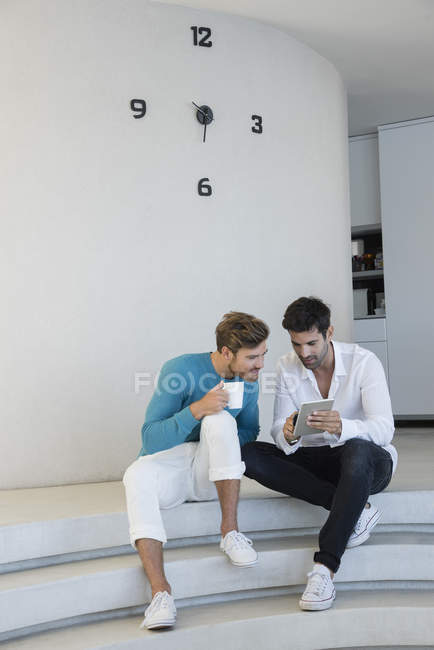 Heureux amis masculins utilisant tablette numérique sur les escaliers — Photo de stock