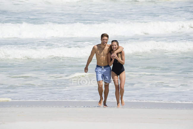 Portrait of happy couple walking on sandy beach — Stock Photo