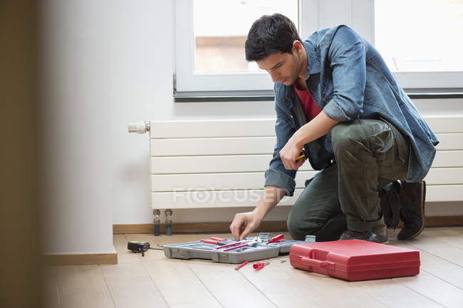 Technicien masculin organisant boîte à outils sur le sol — Photo de stock