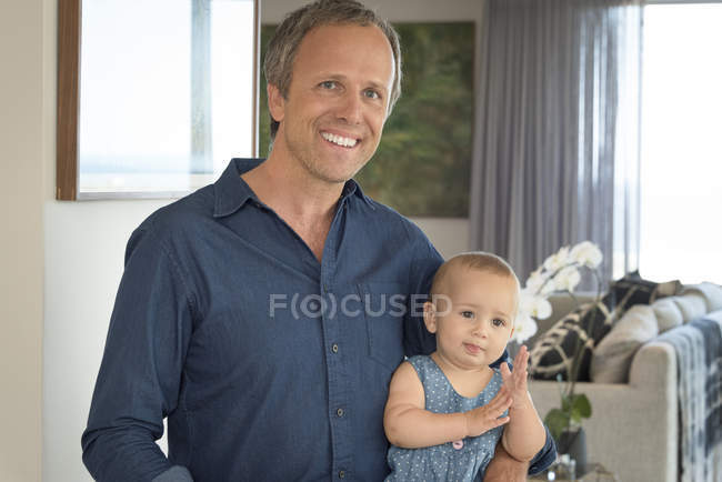 Portrait of happy mature man sitting with little daughter at home — Stock Photo