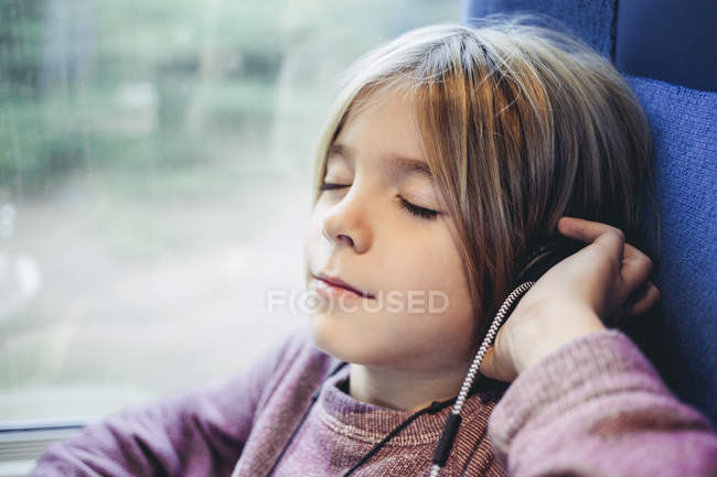 Хлопчик слухає музику з навушниками в громадському транспорті — стокове фото