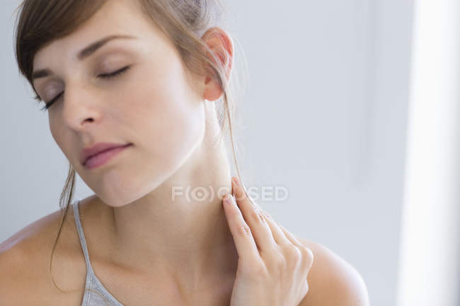 Close-up de jovem mulher massageando pescoço em fundo cinza — Fotografia de Stock