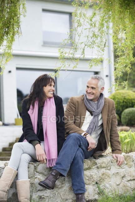 Pareja romántica sentada en el jardín y sonriendo - foto de stock
