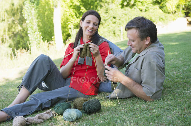 Mature couple knitting together in summer garden — Stock Photo