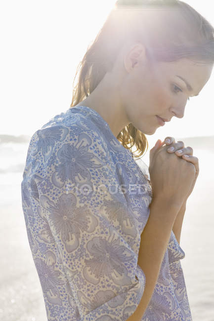 Gros plan d'une femme réfléchie priant sur la plage — Photo de stock