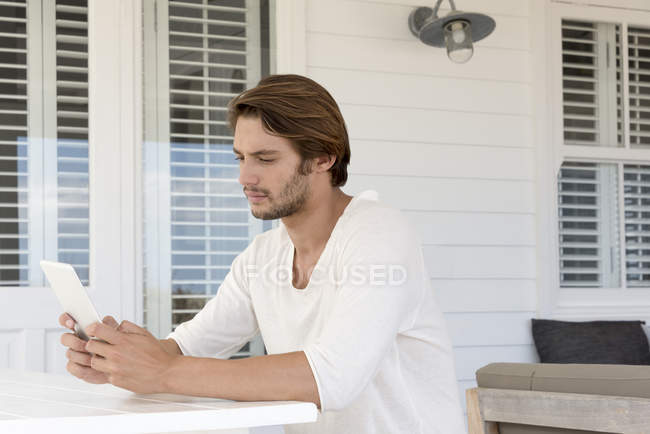 Молодой человек с цифровой табличкой на террасе — стоковое фото