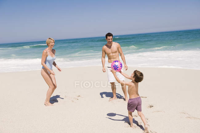 Heureux famille jouer avec beach ball sur le sable — Photo de stock