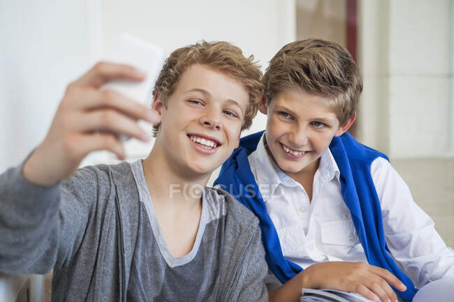 Two teenage boys taking a picture of themselves with a mobile phone — Stock Photo