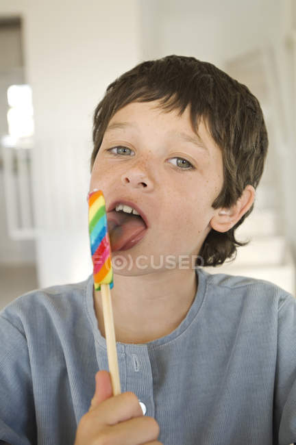 Retrato de menino lambendo pirulito em casa — Fotografia de Stock
