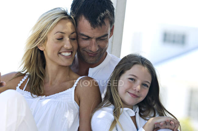 Родители и дочь улыбаются перед камерой, на улице — стоковое фото