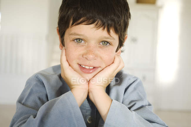 Маленький весняний хлопчик посміхається і дивиться на камеру на дерев'яний стіл — стокове фото
