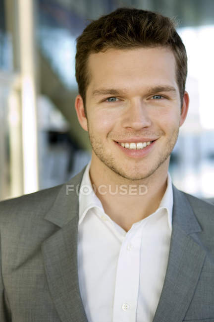 Портрет молодого бізнесмена, який посміхається на розмитому тлі — стокове фото