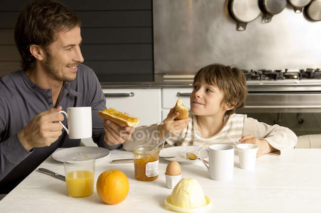 Homem adulto médio tomando café da manhã com seu filho — Fotografia de Stock