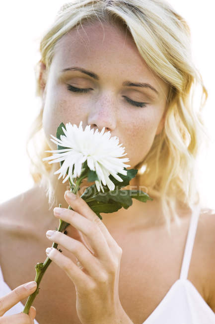 Портрет молодої блондинки з закритими очима тримає білу квітку — стокове фото