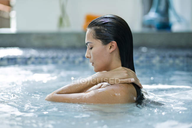 Жінка з мокрим волоссям розслабляється в басейні — стокове фото