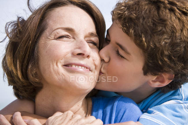 Щасливий хлопчик цілує бабусю на відкритому повітрі — стокове фото