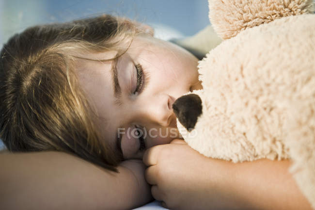Nahaufnahme eines kleinen Mädchens, das mit Teddybär schläft — Stockfoto