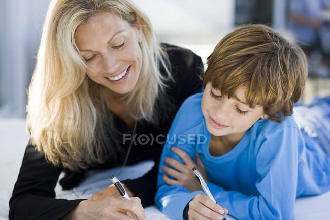Mujer ayudando a su hijo en su tarea - foto de stock