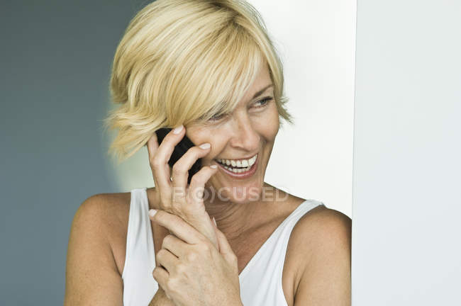 Смеющаяся взрослая женщина разговаривает по мобильному телефону — стоковое фото