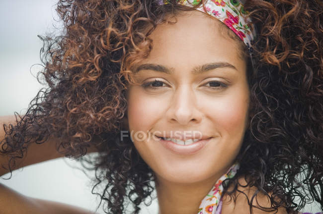 Portrait of woman with bandanna in curly hair smiling — Stock Photo