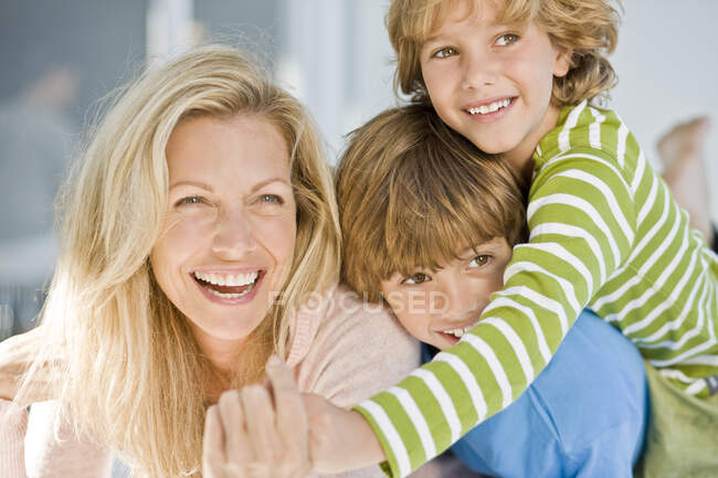 Mujer sonriendo con sus dos hijos - foto de stock