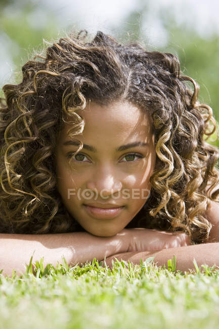 Portrait of latin american teenage girl lying on grass — Stock Photo