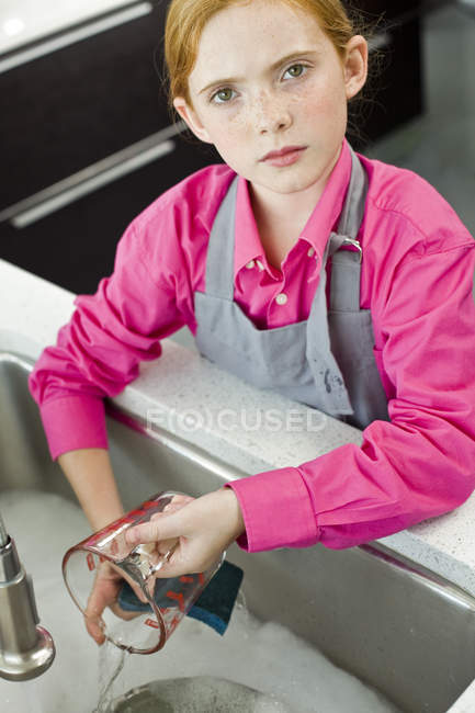 Close-up of  ginger girl washing measuring jug in sink — Stock Photo