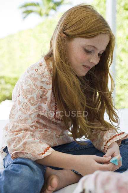 Close-up of ginger girl playing with toys outdoors — Stock Photo