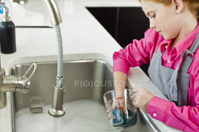 Zenzero ragazza lavaggio misurazione brocca in lavandino — Foto stock