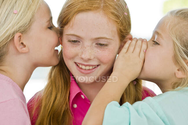 Dos chicas susurrando a otra chica - foto de stock