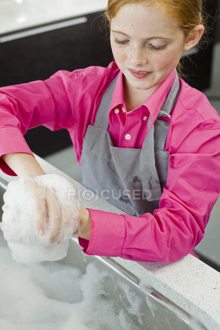 Close-up de sorrindo gengibre menina lavar jarro de medição na pia — Fotografia de Stock